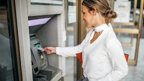 Person putting their debit card into an ATM.