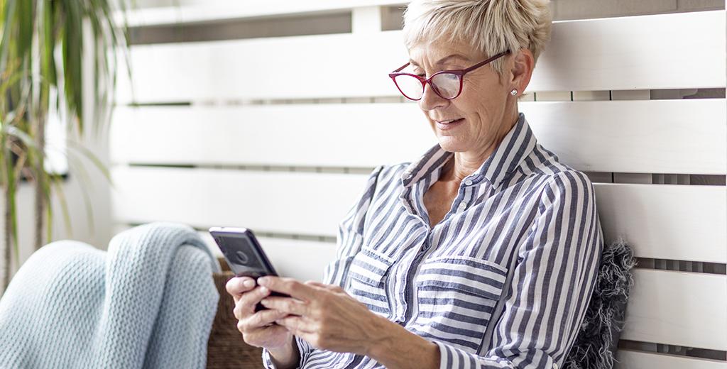 A lady sitting outside scrolling on her phone. 